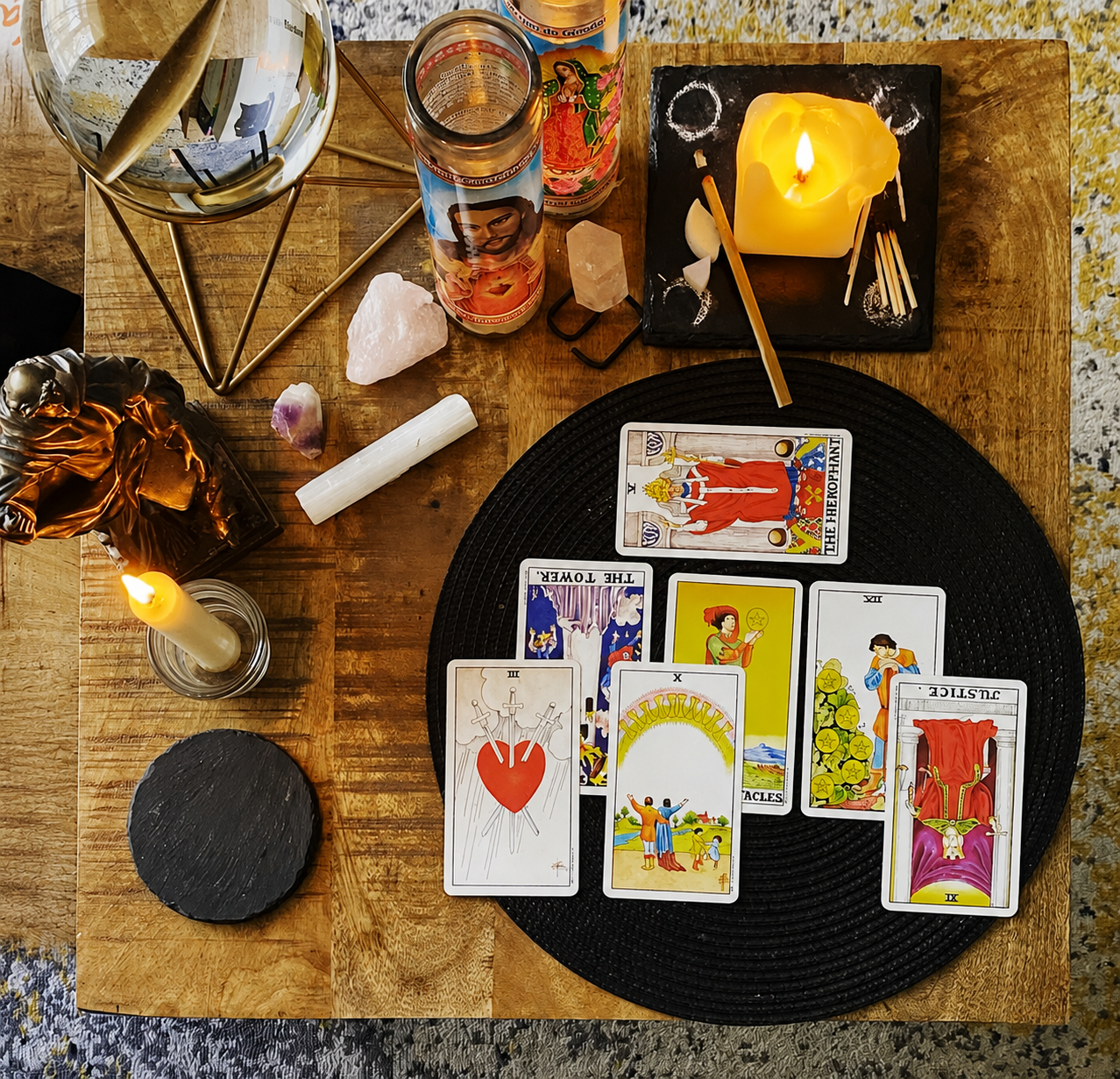 Tarot cards, candles, crystals and a journal on a wooden table